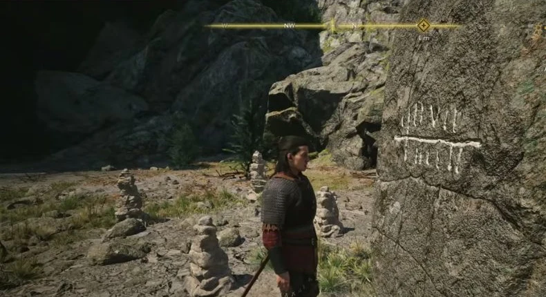Inspect the white glyph on the tall stone among the small cairns.
